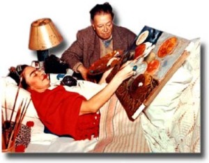 photgraph of frida laying in bed painting.  Diego Rivera is next to her, looking on and holding her palette.