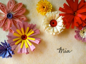 red, pink, purple and yellow paper flowers on a card that says "mia."